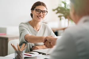 client and business owner shake hands across a table. 