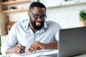 worker takes notes while attending a virtual webinar.