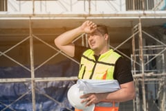 Male construction engineer worker working outside, tired and showing signs of heat stress.
