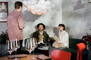Waiter takes orders from a couple seated at a table.