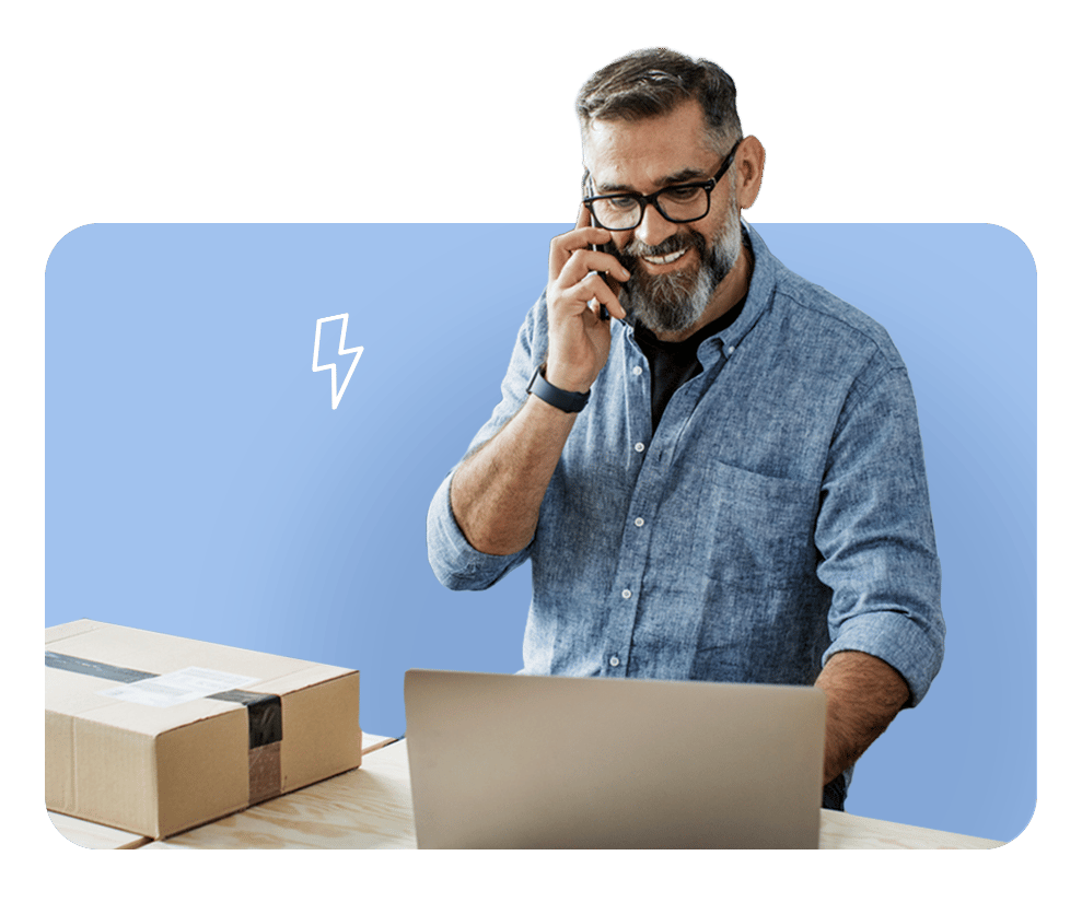 Man smiling while on phone at desk, illustrating FrankCrum’s intuitive HR technology platform that simplifies self-service and operations