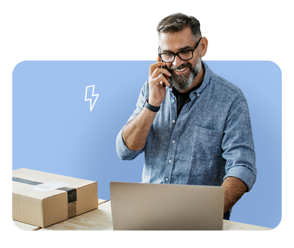 Man smiling while on phone at desk, illustrating FrankCrum’s intuitive HR technology platform that simplifies self-service and operations