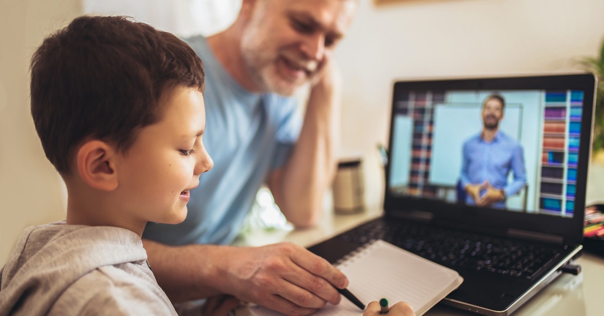 Parent helps young child with homework while attending a virtual class
